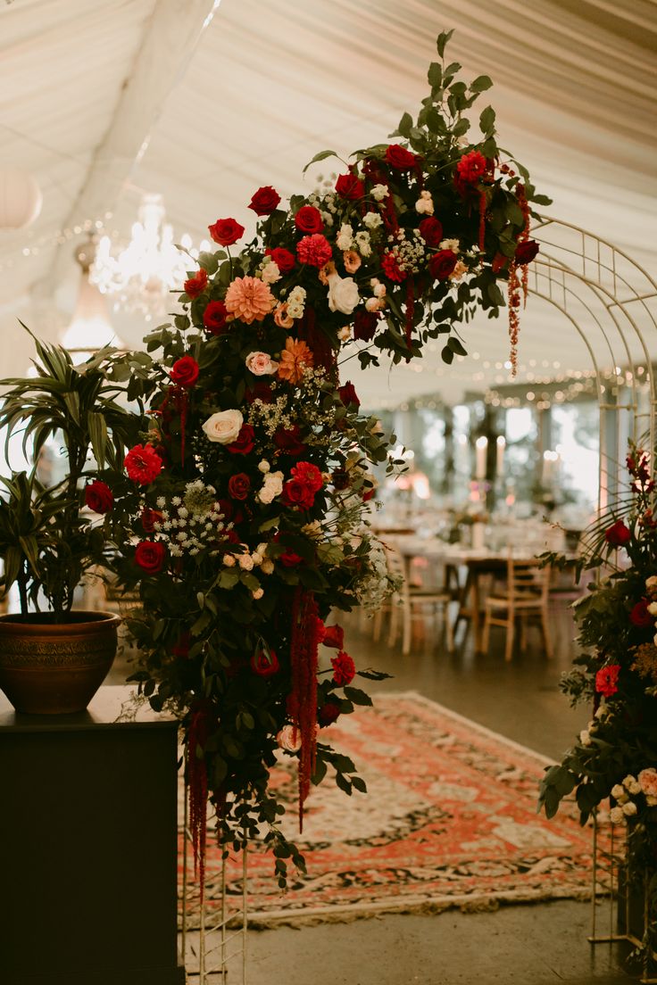 an arch decorated with flowers and greenery in a tented area for a wedding reception