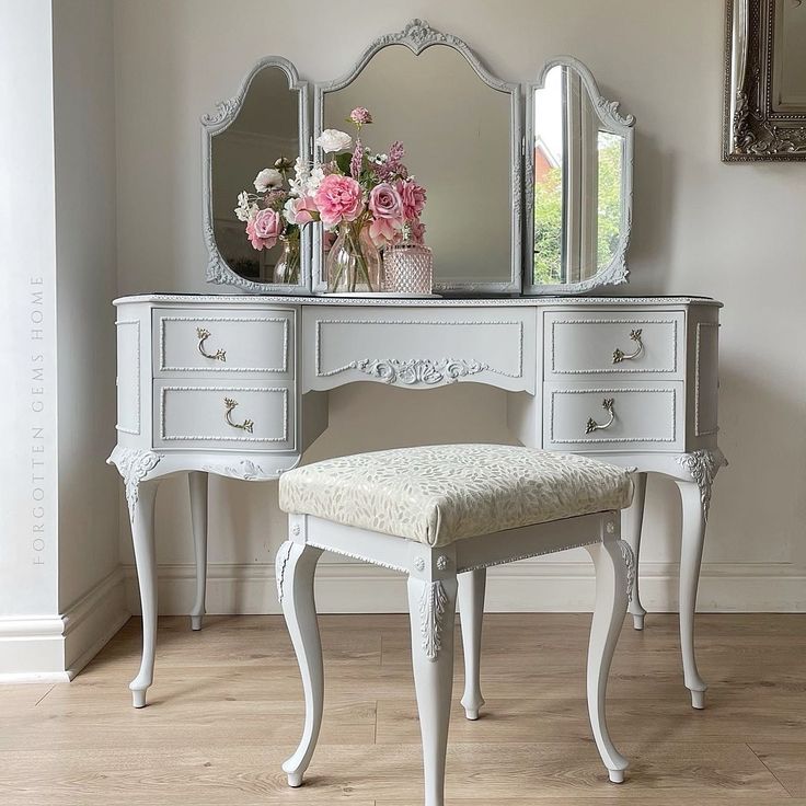 a white dressing table with a mirror and stool in front of it on top of a hard wood floor