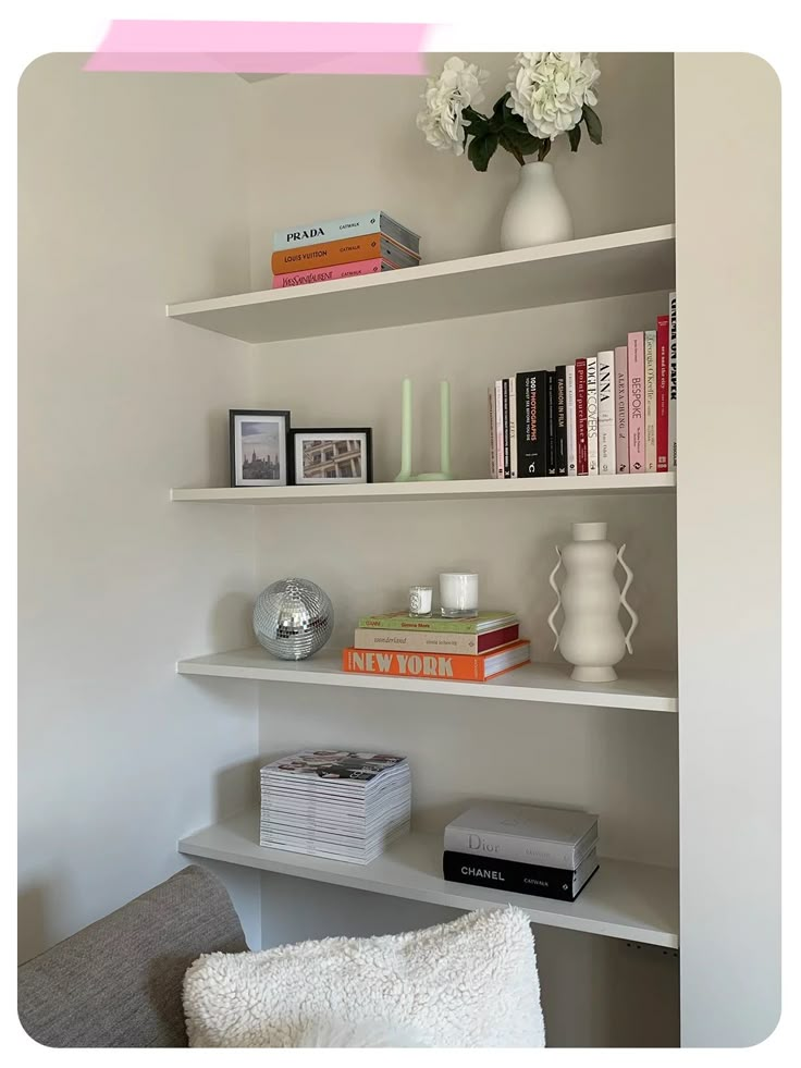 a white shelf with books and vases on it