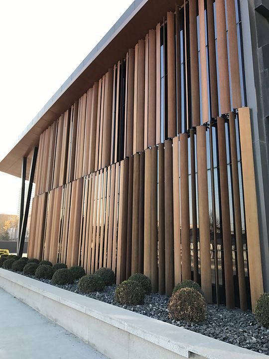 a building with wooden slats on the side and plants growing in front of it