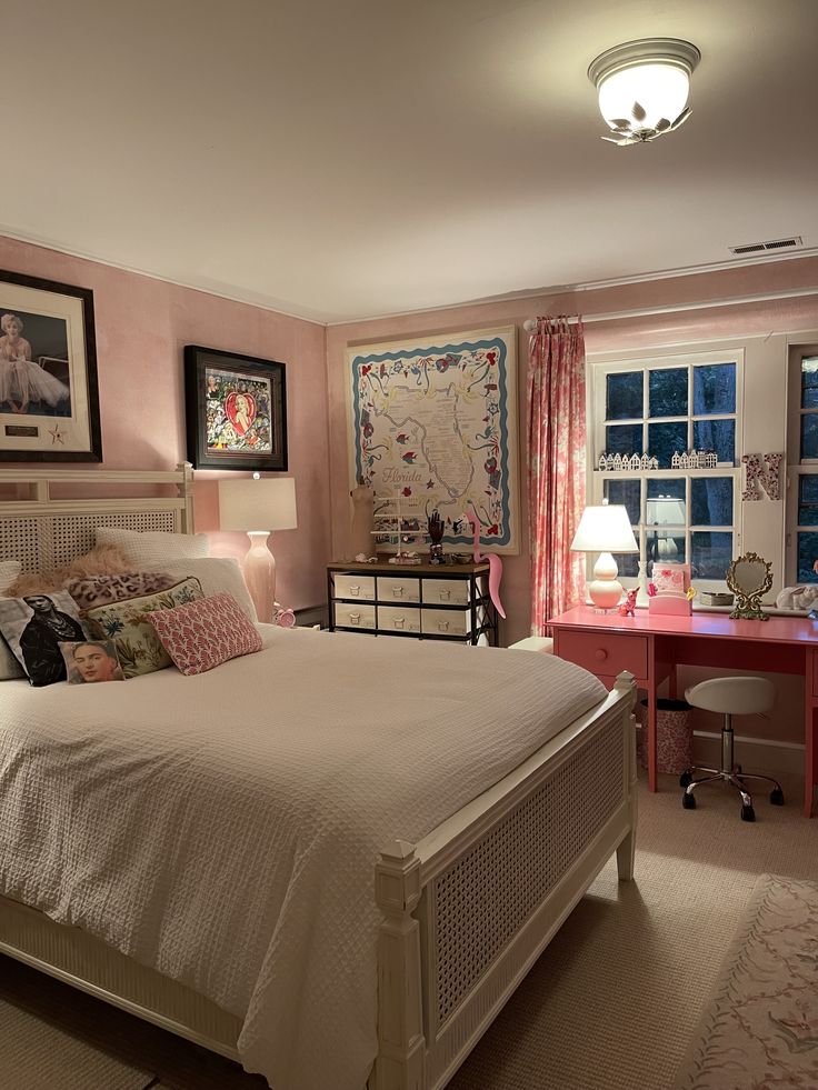 a bedroom with pink walls, white bedding and pictures on the wall above it