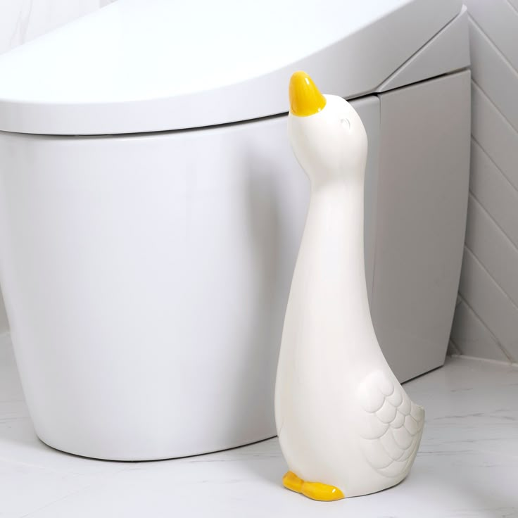 a white duck next to a toilet in a bathroom