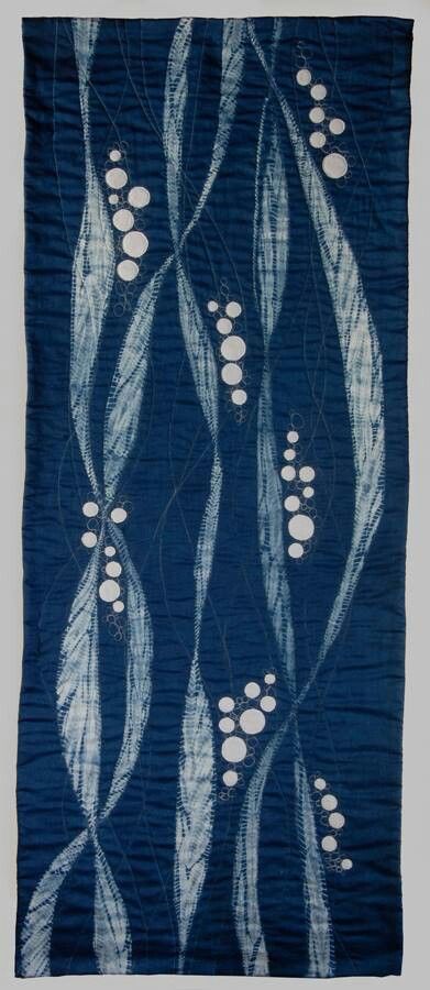 a blue and white wall hanging with circles on it's sides, in the shape of leaves