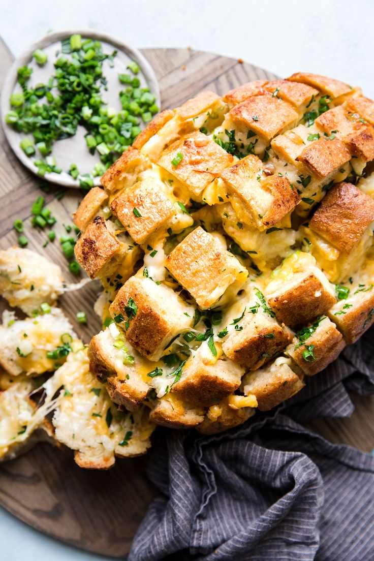 a cheesy bread dish on a cutting board next to some peas and other food