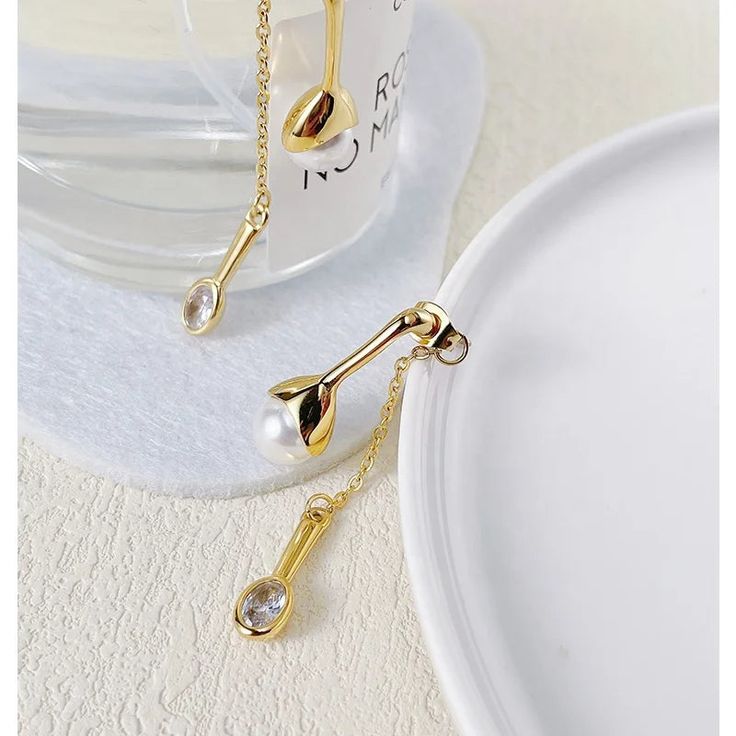 Introducing the Selena Pearl Earrings, a modern interpretation of classic elegance. These stunning earrings feature a large pearl adorned with a drop-style single stone, creating a captivating and contemporary design that is sure to turn heads. Crafted with meticulous attention to detail, the Selena Pearl Earrings are plated with luxurious 18K gold over stainless steel, ensuring a radiant and long-lasting finish. Their unique combination of elements adds a touch of sophistication to any outfit, Modern White Dangle Pearl Earrings, Modern Pearl Pendant Earrings, Modern Long Drop Pearl Earrings, Modern Gold Long Drop Pearl Earrings, Modern Drop Pearl Earrings, Modern Pearl Drop Earrings With Pendant, Modern Drop Pearl Earrings As Gift, Modern Drop Pearl Earrings With Charm, Modern Drop Pearl Earrings With Pearl Charm