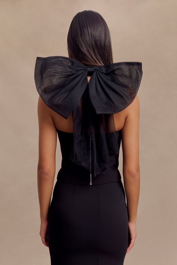 Adorned with a bow. The MARYAM Tulle Bow Top is a statement piece that combines elegance with a touch of whimsy. Featuring a princess neckline and a fitted bodice, this top offers a flattering and sophisticated silhouette. The mesh functional halter adds a delicate touch, while the tulle-lined back bow creates a stunning focal point. With a centre-back zip for easy wear, this top pairs beautifully with an A-line skirt for a chic and graceful ensemble. Fully lined for comfort, the Maryam Tulle Bo Elegant Party Top With Bow, Feminine Party Blouse With Bow, Elegant Sleeveless Blouse With Bow, Chic Tie-back Blouse For Parties, Chic Fitted Bodice Sleeveless Tops, Chic Sleeveless Top With Fitted Bodice, Elegant Sleeveless Top With Bow Tie Back, Formal Sleeveless Top With Bow, Elegant Tops With Satin Bow For Spring