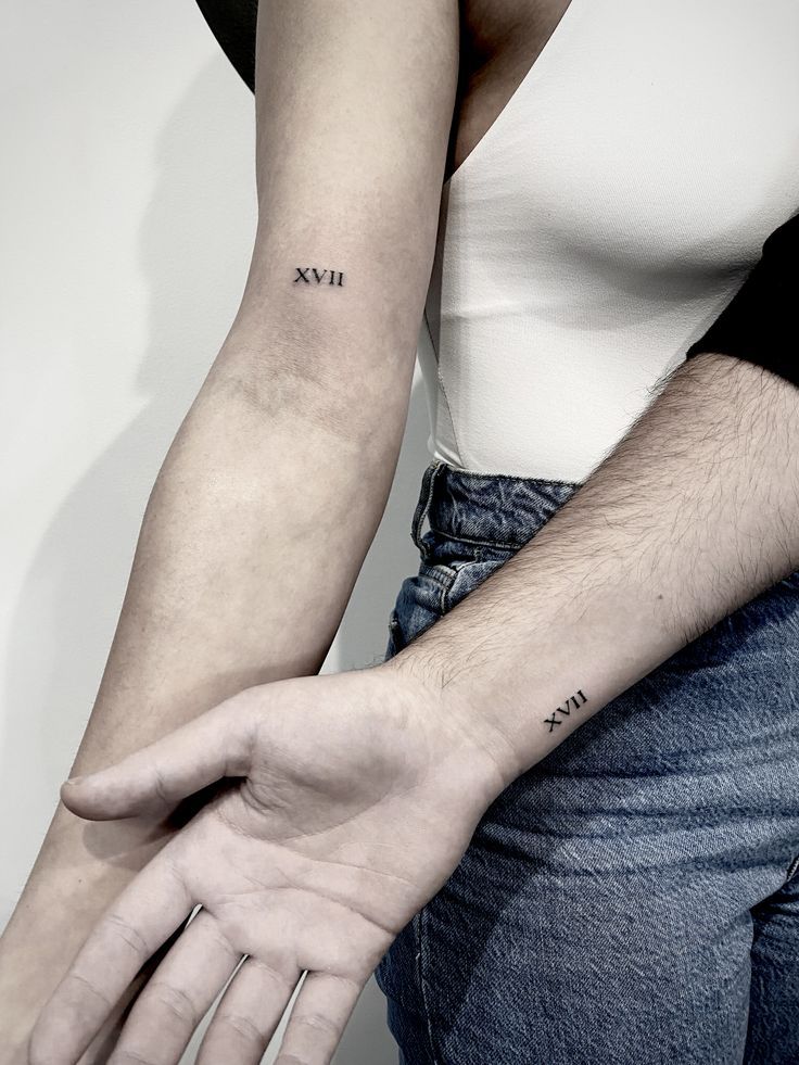 two people holding hands with tattoos on their arms and the word love tattooed on them