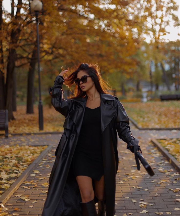 a woman is walking down the street with her hair blowing in the wind and holding an umbrella