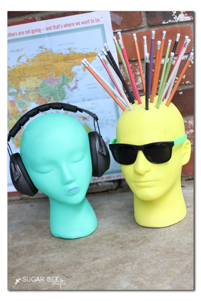 two plastic heads with headphones on and one has a neon colored hairbrush holder in the shape of a man's head