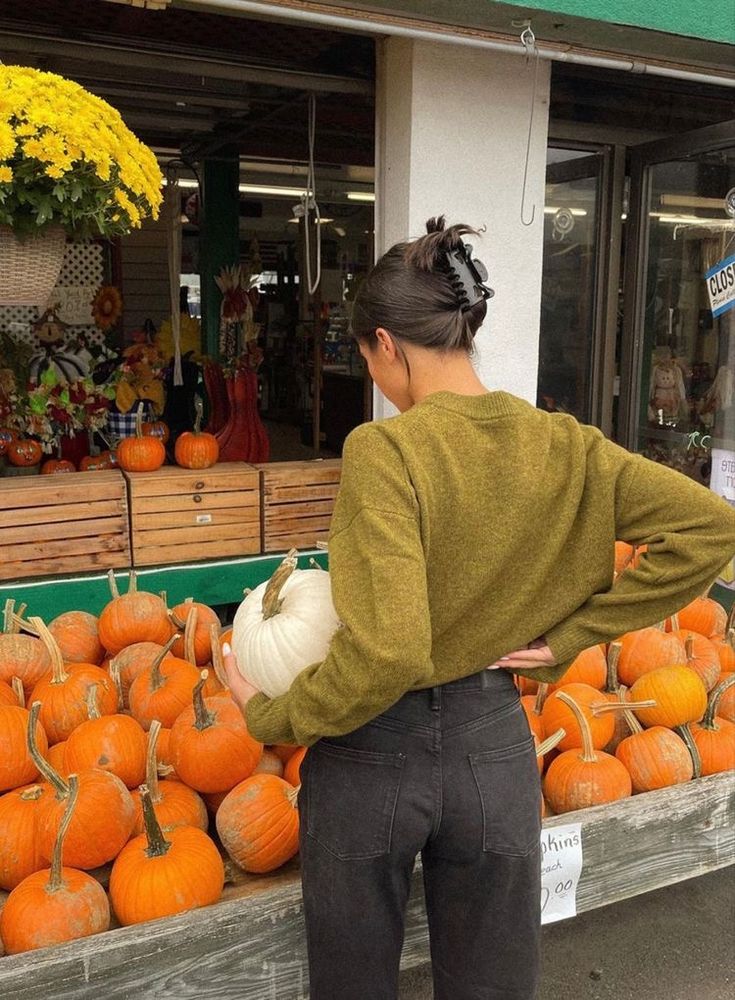 a woman standing in front of a display of pumpkins