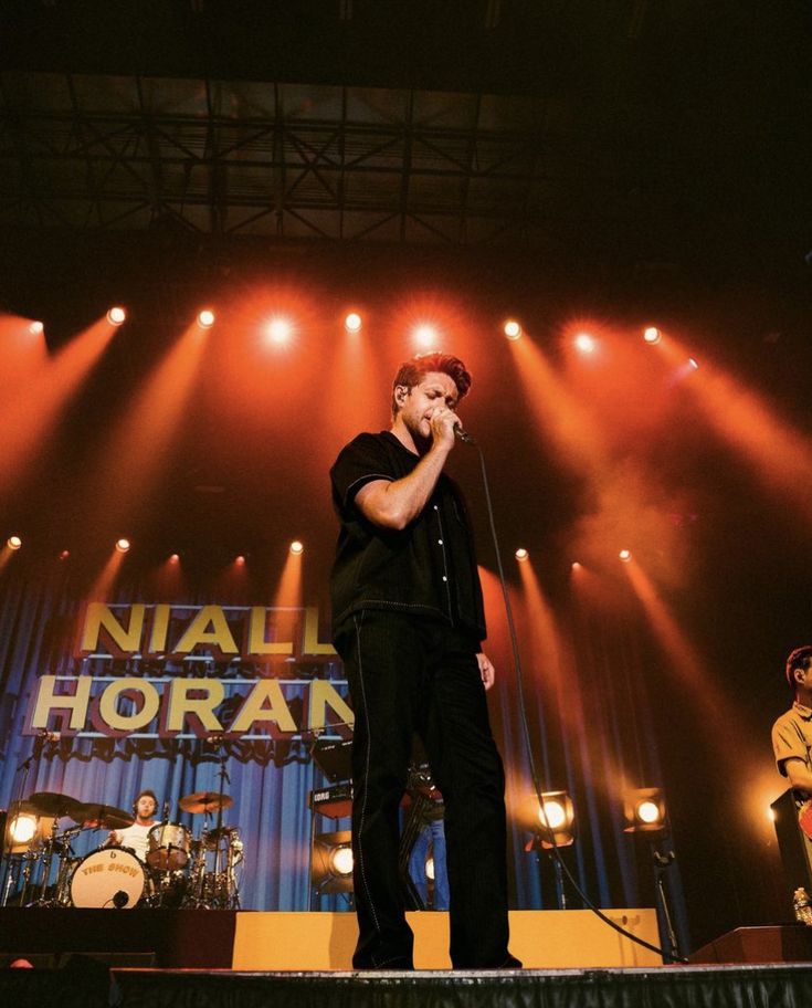 a man standing on top of a stage holding a microphone in front of his face