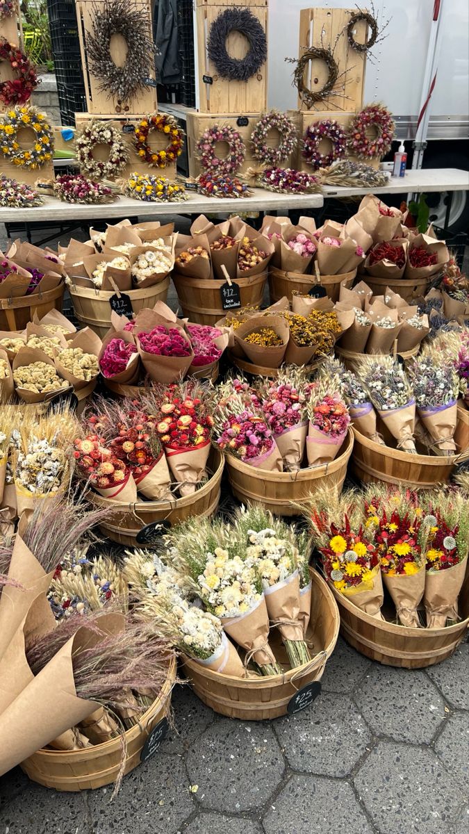 baskets filled with flowers sitting on top of a stone floor next to wooden crates full of dried flowers