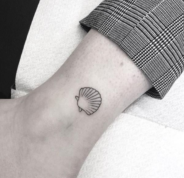 a small seashell tattoo on the wrist