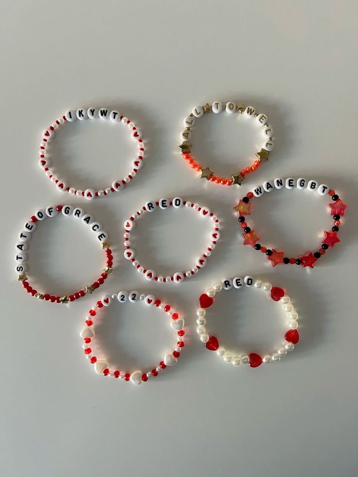 six beaded bracelets with red, white and black beads sitting on top of each other