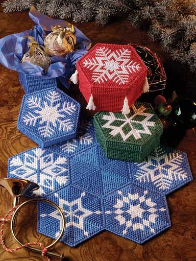 several knitted items are sitting on the floor next to a christmas tree and other decorations