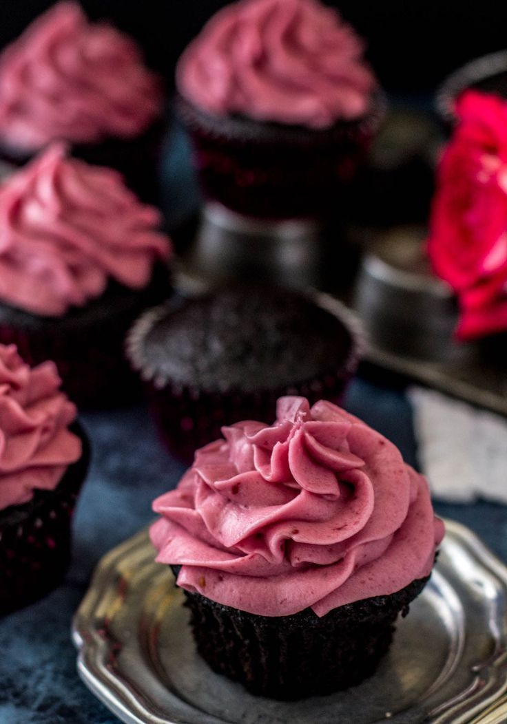 cupcakes with pink frosting sitting on a silver plate