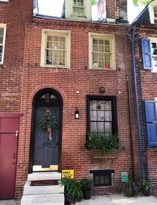 an old brick building with blue shutters on the front and second story window boxes