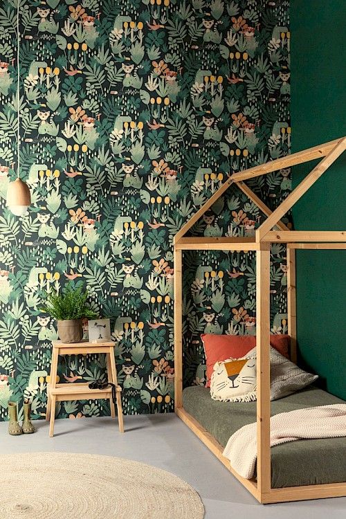 a bedroom with green wallpaper and a wooden dollhouse bed in the foreground