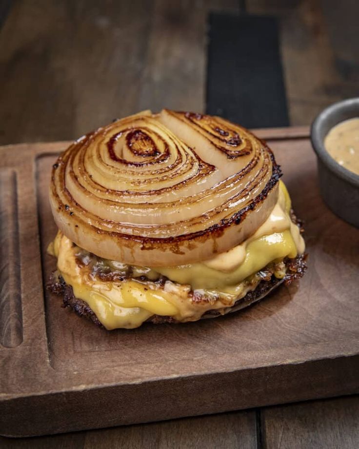 an onion and cheese sandwich on a wooden cutting board