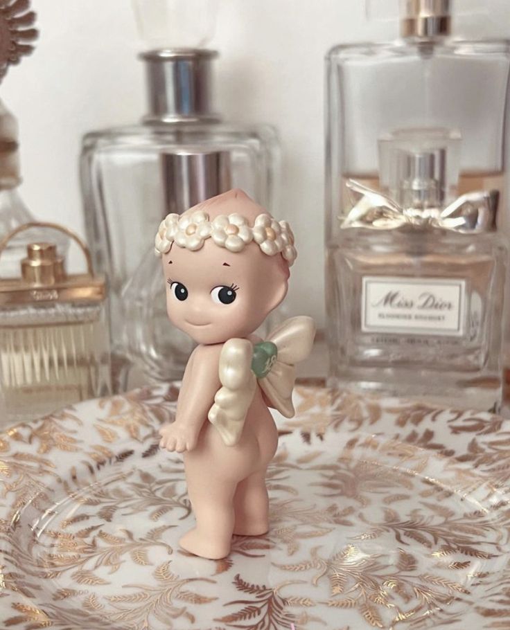 a little angel figurine sitting on top of a table next to perfume bottles