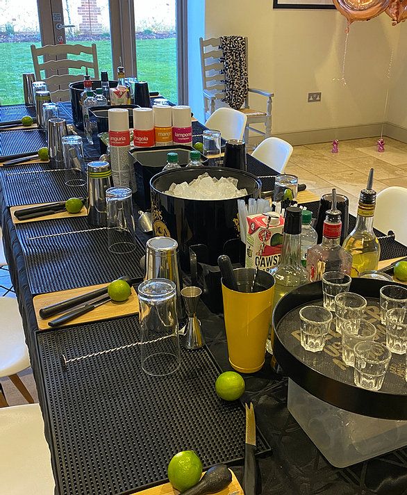 a long table is set up with empty glasses, bottles and utensils on it