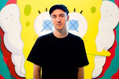 a man standing in front of a colorful wall with a spongebob painting on it