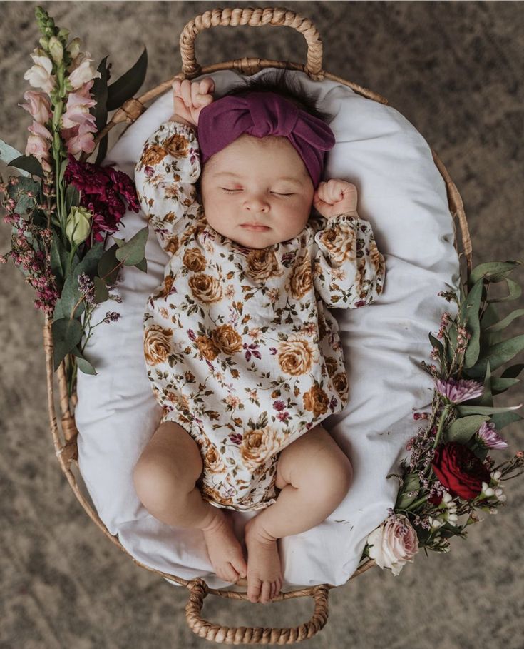 a baby is sleeping in a basket with flowers