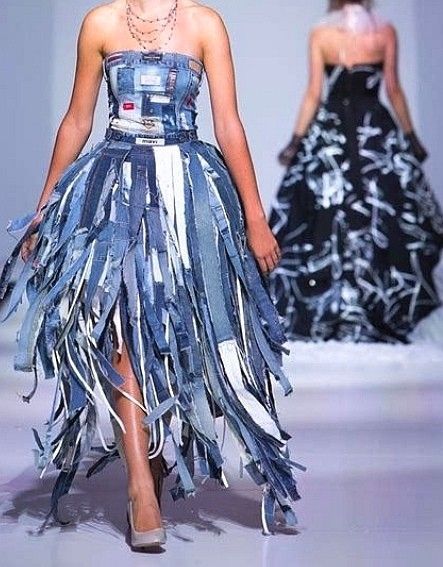 a woman walking down a runway wearing a dress made out of jeans and fringes