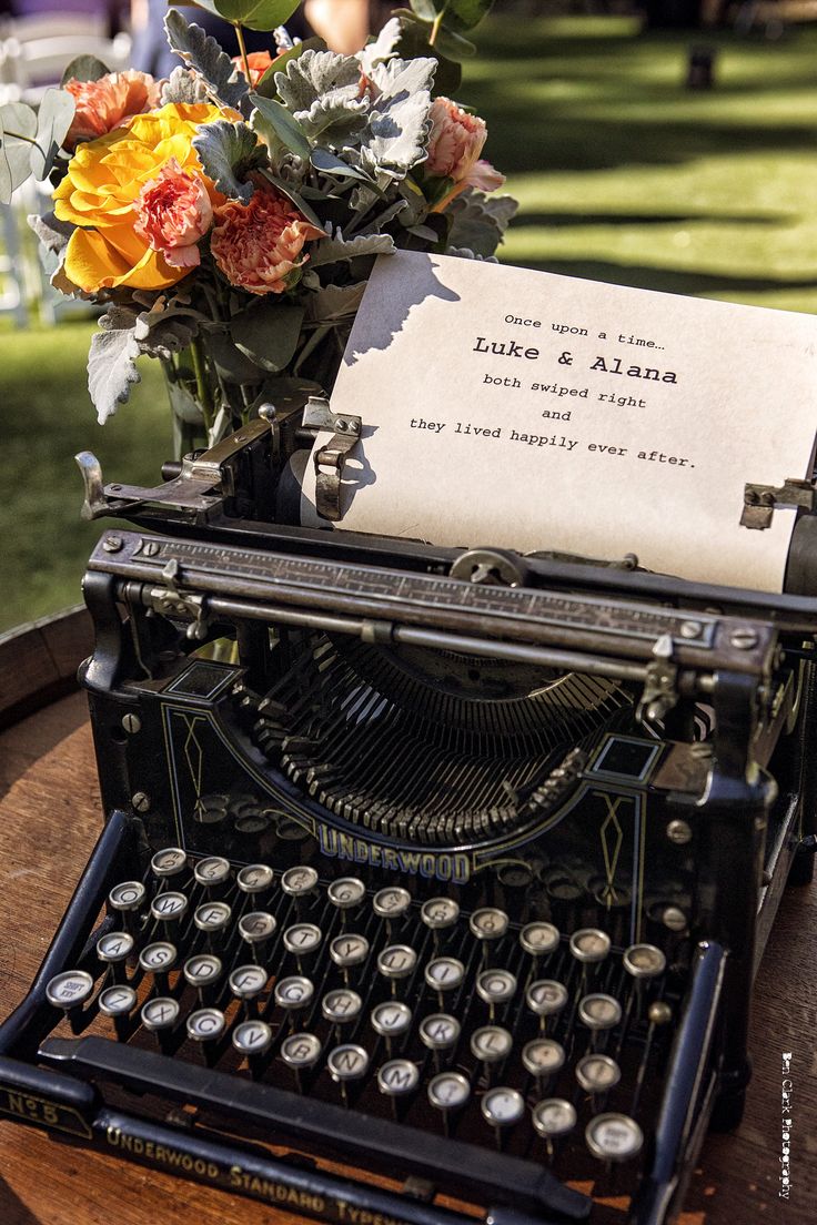 an old - fashioned typewriter with flowers and a note on it sitting on a table