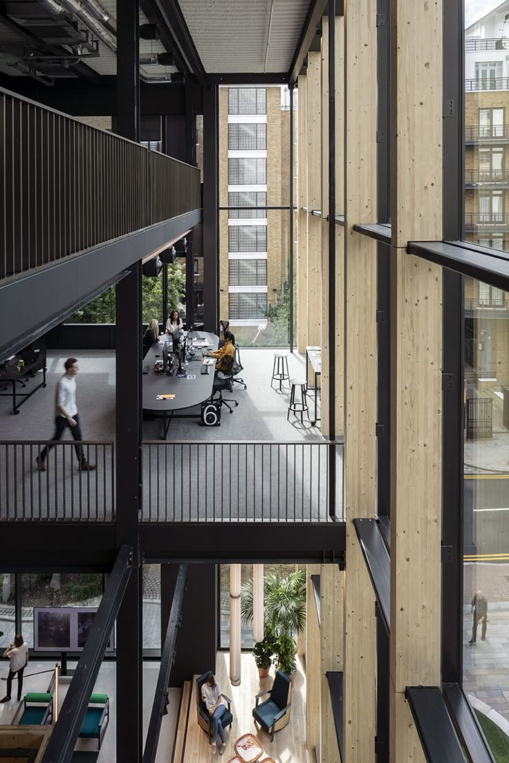 the interior of an office building with lots of windows and people working on their laptops