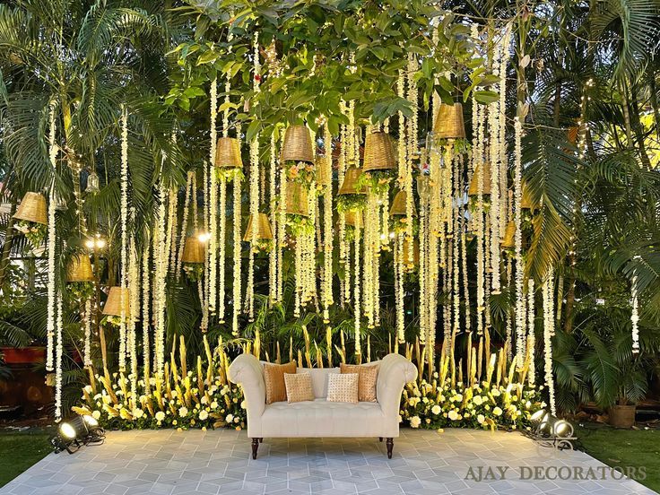 a white couch sitting in front of a lush green wall covered with hanging planters