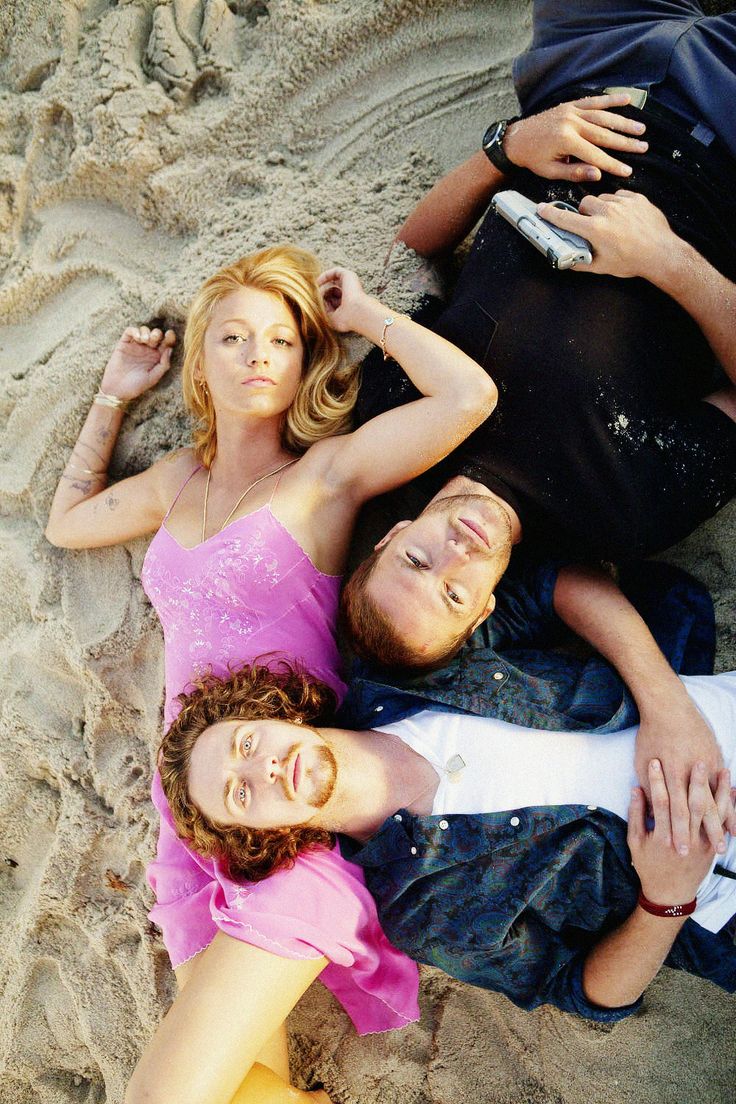 three people laying in the sand together