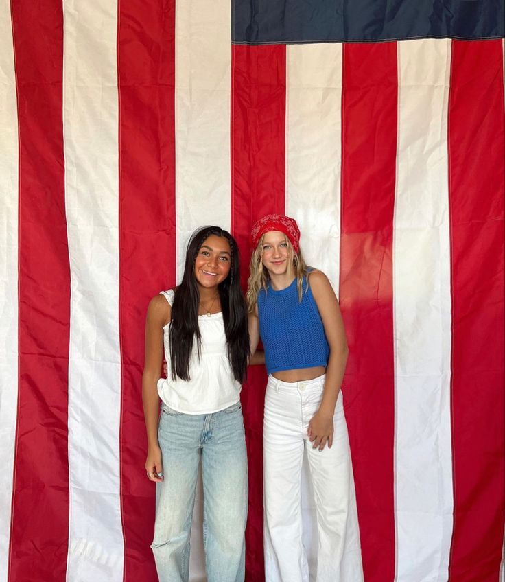 two girls standing in front of an american flag