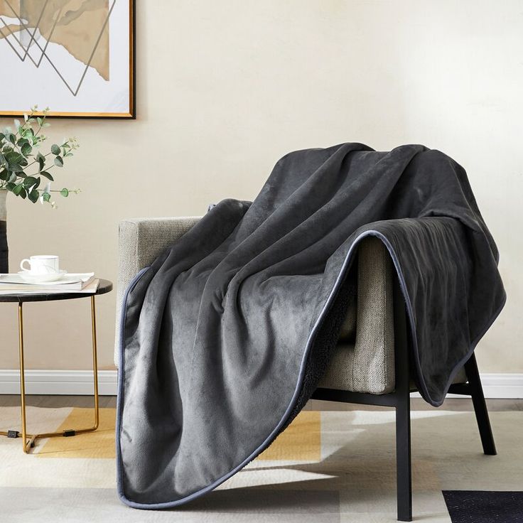 a couch with a blanket on it next to a coffee table and potted plant