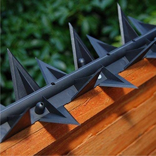 several metal spikes on top of a wooden fence