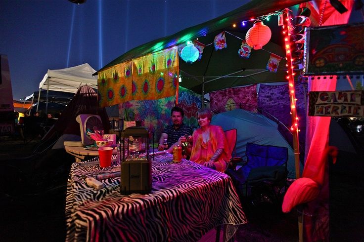 a man sitting at a table in front of a tent with lights and decorations on it