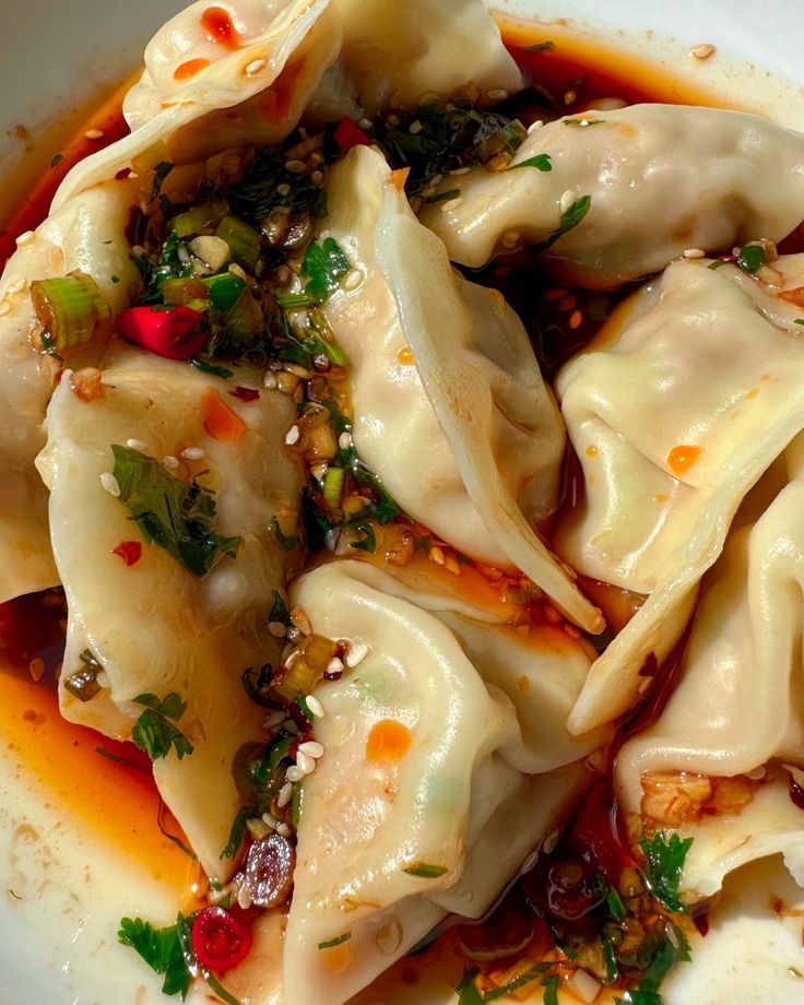 dumplings with sauce and herbs in a white bowl