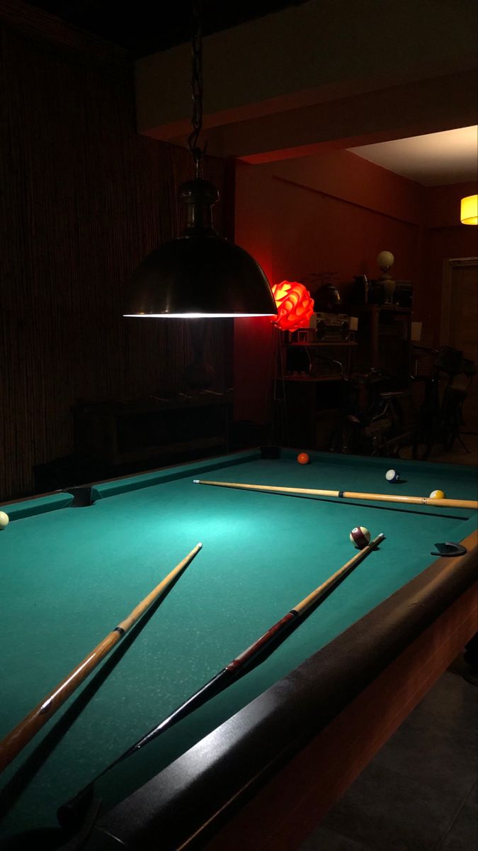 a pool table with cues and cues on it in a room that is dimly lit