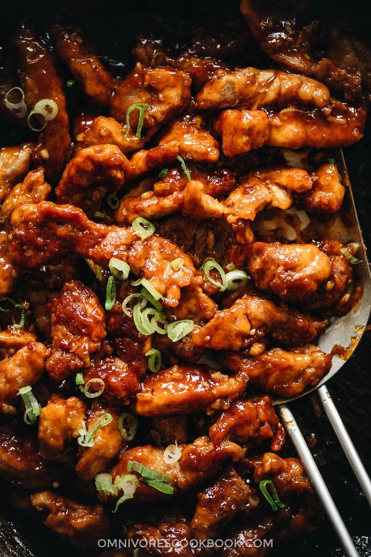 chicken wings with sauce and green onions in a skillet, ready to be eaten