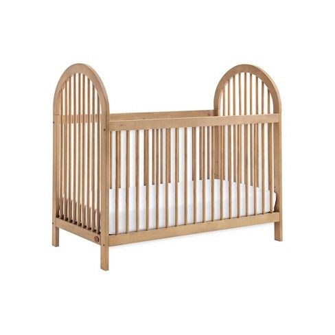 a wooden crib with white sheets in it