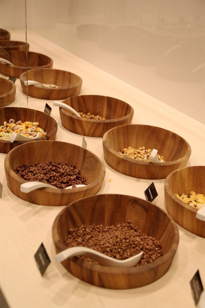 wooden bowls filled with cereal and cereal bars on display in a glass case at a store