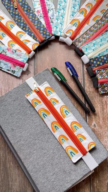 a notebook covered in different colored pencils next to some scissors and pens on a wooden table