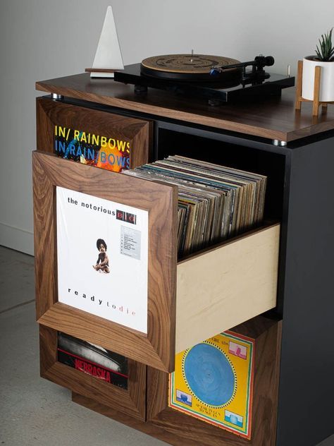 a record player is sitting on top of a wooden cabinet with records in the drawers