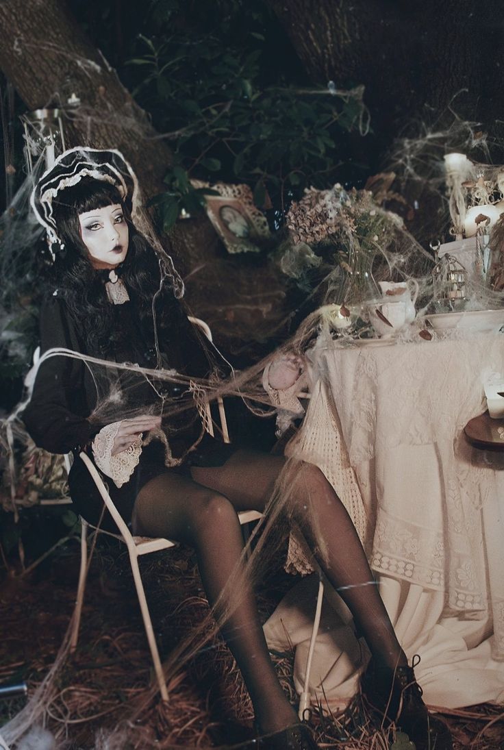 a woman sitting in a chair next to a table with candles and decorations on it