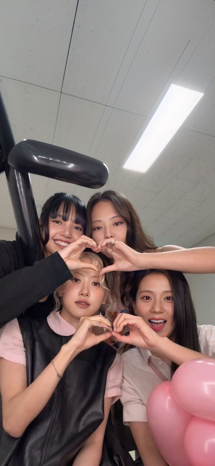 group of young women making heart shape with their hands while sitting in a chair together