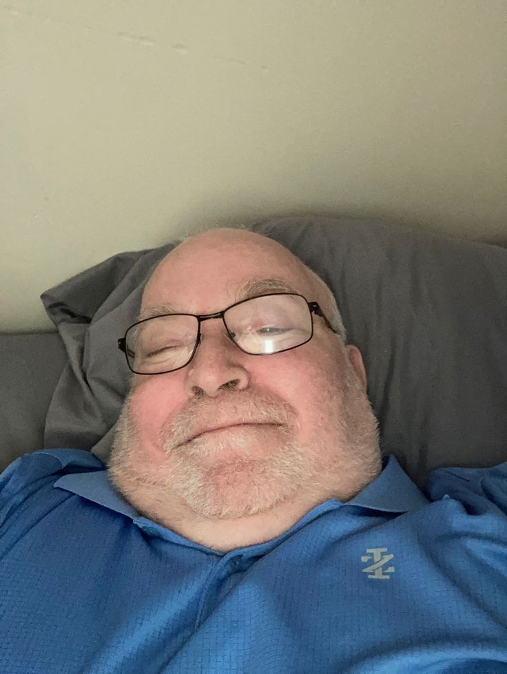 an older man with glasses is laying down