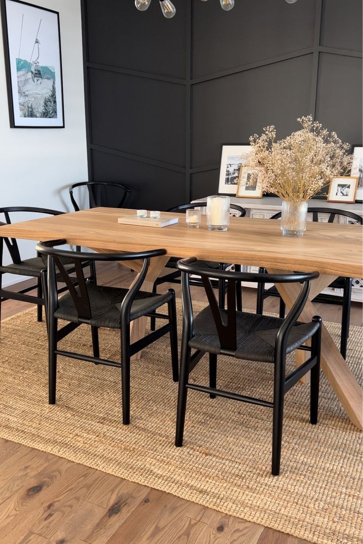 a dining room table with chairs and pictures on the wall behind it, along with an area rug