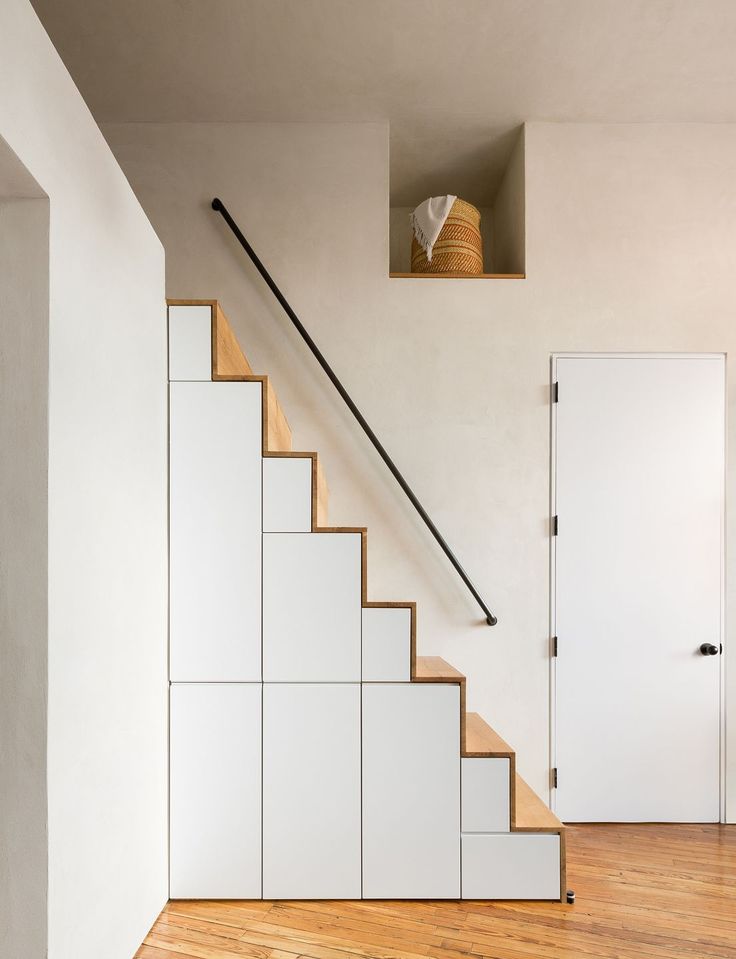 an empty room with white walls and wooden floors, stairs leading up to the second floor