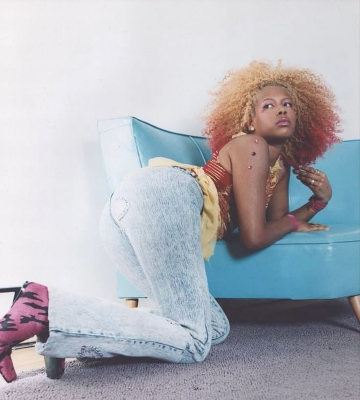 a woman sitting on top of a blue couch next to a pink shoe and rug