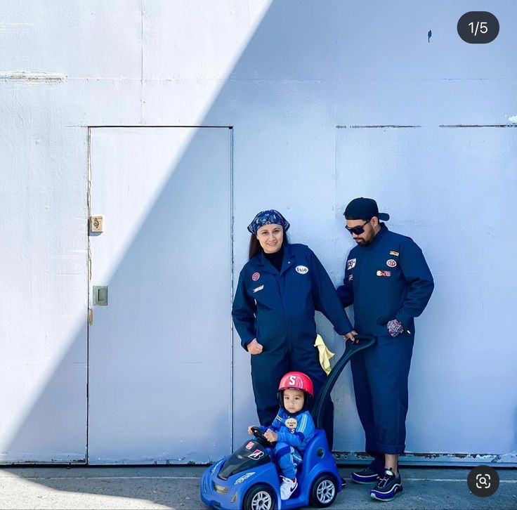 a man and woman standing next to a child in a toy car